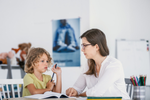 A young female tutor having a lesson with an absentminded child