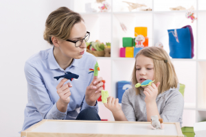 Female teacher using colorful toys during play therapy with child
